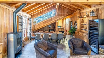 Un intérieur en bois comprenant un coin repas, des sièges et un poêle à bois encastré.