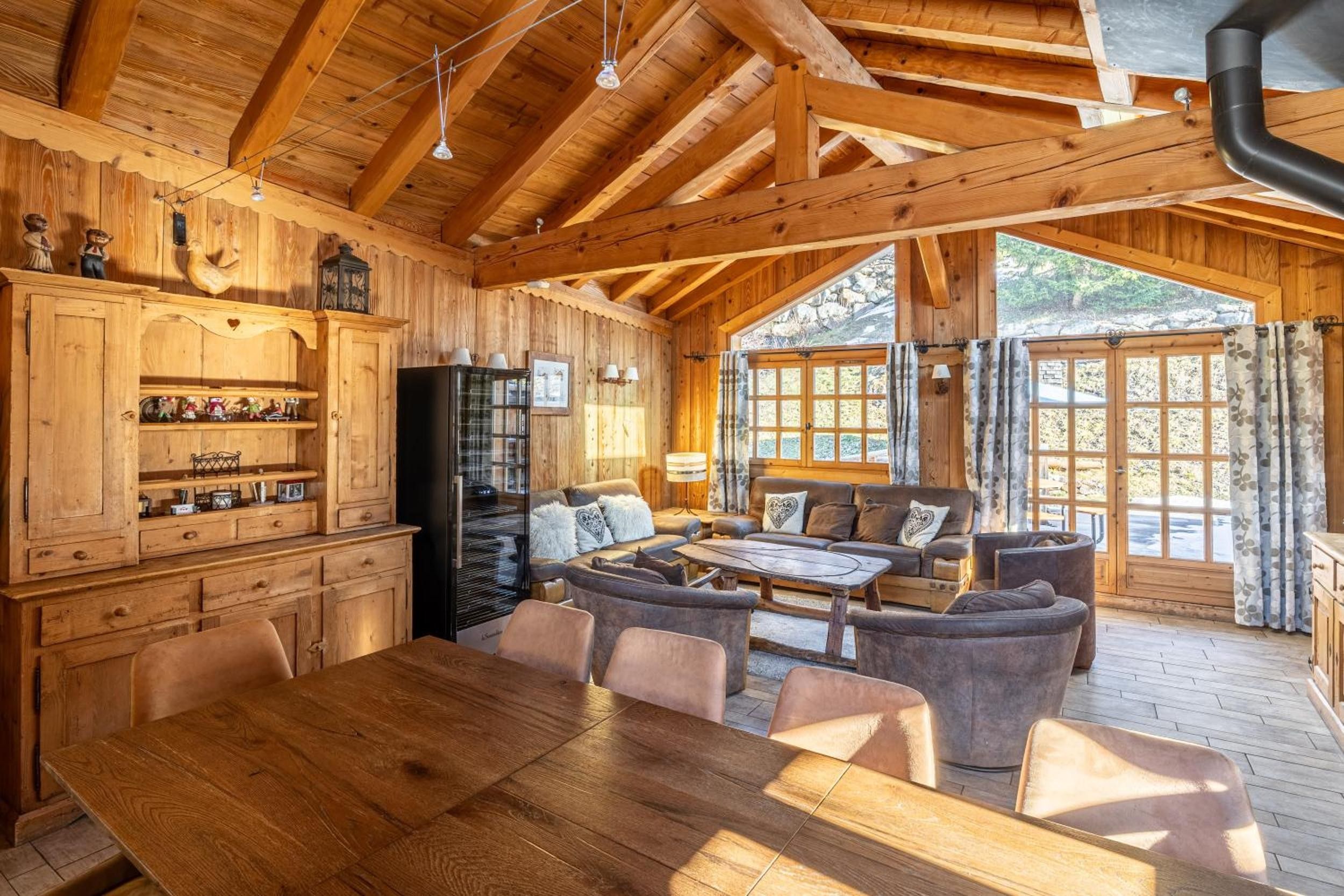 Un intérieur en bois comprenant un coin repas, des canapés et une grande fenêtre.
