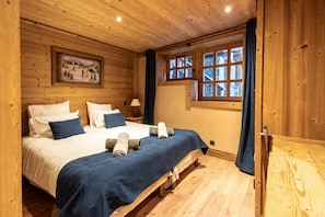 Une pièce en bois avec un lit, un tableau et une fenêtre avec des rideaux.