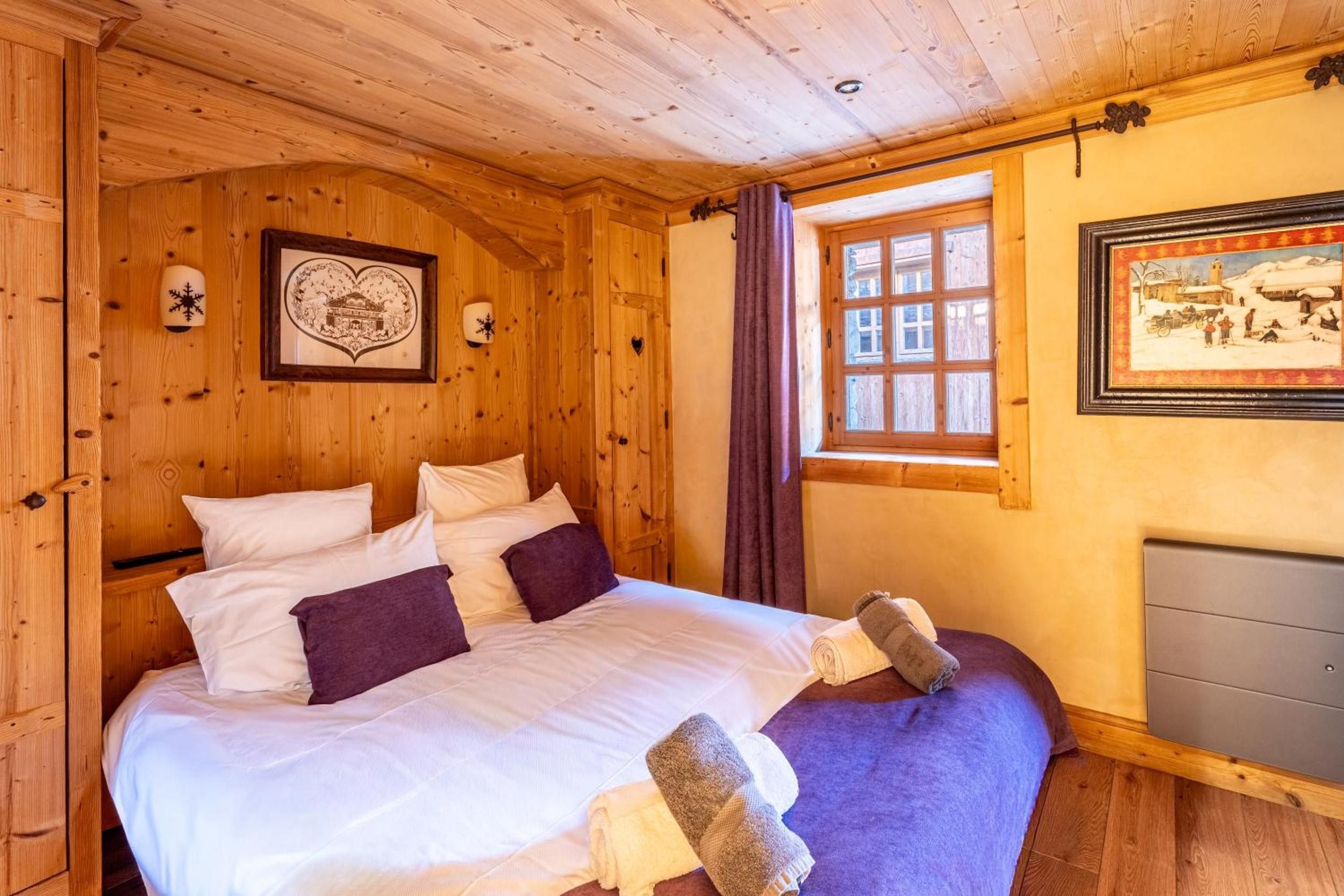 Une pièce en bois avec un lit, une fenêtre et une cheminée.
