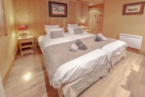 A hotel room with a large bed, wooden walls, a nightstand with a lamp, and two framed pictures on the wall.