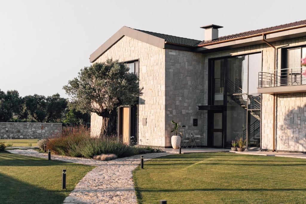 A modern house with a stone facade, large windows, and a balcony.