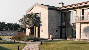 Ein modernes Haus mit Natursteinfassade, großen Fenstern und einem Balkon.