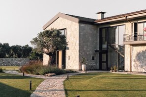 Una casa moderna con fachada de piedra, ventanas amplias y un balcón.