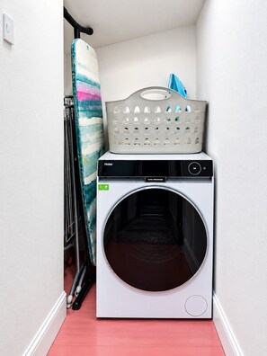 A compact laundry area with a front-loading washing machine and a drying rack. - Balvonie House, Grand Scottish Mansion, Hot Tub with Island Views. 12 Bedrooms (Skelmorlie)
