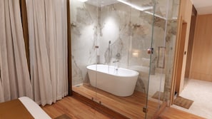 Une salle de bain moderne avec une baignoire sur pieds, une douche à parois de verre et un revêtement de sol en bois.