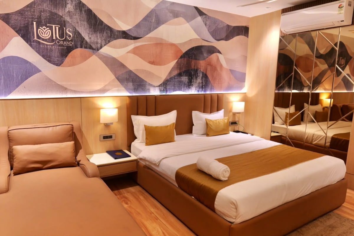 Une chambre d’hôtel avec un grand lit, un canapé séparé, une table de chevet avec une lampe et une œuvre d’art accrochée au mur.