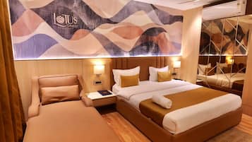 A hotel room with a large bed, a separate sofa, a nightstand with a lamp, and a wall-mounted artwork.
