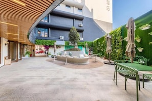 Une cour d’hôtel aménagée avec un espace salon, du mobilier d’extérieur et un mur végétal.