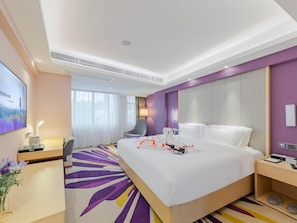 Une chambre d’hôtel avec un grand lit, un bureau, une chaise et un téléviseur.