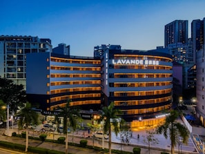 Un hôtel à plusieurs étages, reconnaissable à son grand panneau « LAVANDE », qui présente une architecture moderne avec des balcons et une façade bien éclairée.