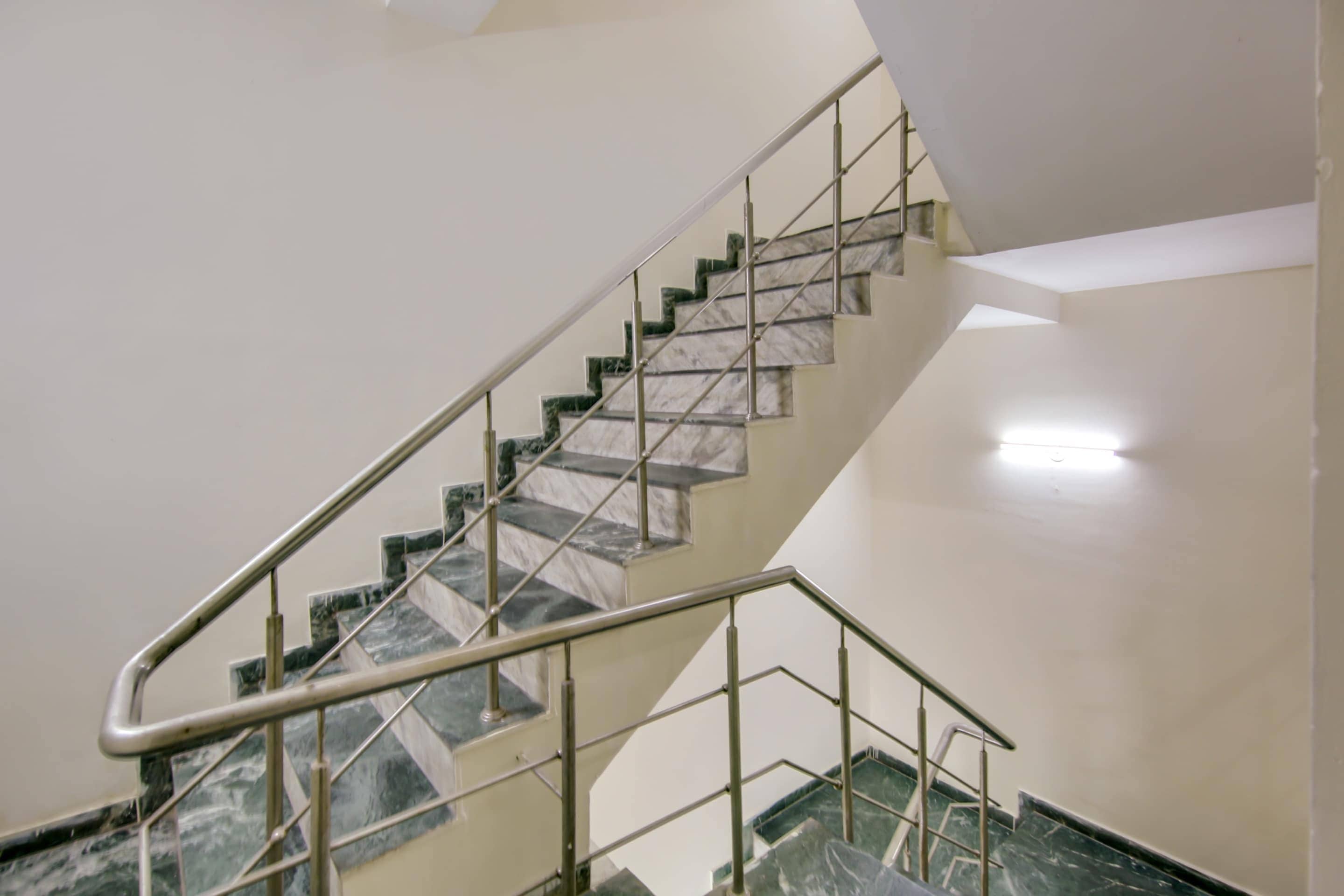 Un escalier avec une rampe métallique et des marches en marbre.