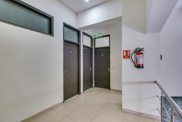 A hallway with doors numbered 204 and 206, a fire exit sign, and a fire extinguisher mounted on the wall. - Hotel O Dream View (Gurgaon)