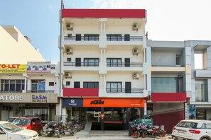 Un edificio de varios pisos con locales comerciales en la planta baja, incluyendo una tienda de motocicletas y un banco.