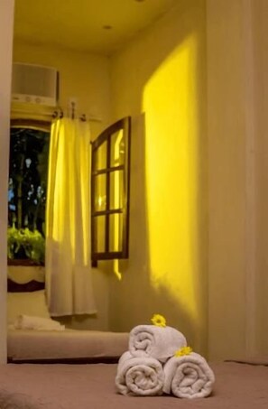 A room with a bed, a window with curtains, and a towel stack. - Dolce Vita Pousada e Mergulho (Angra dos Reis)