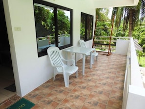 A balcony with a table and chairs, a ladder, and a view of greenery. - Jalyns Resort (Puerto Galera)
