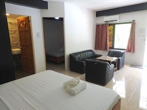 Habitació d'hotel amb un llit, un sofà, una taula petita i una finestra amb cortines.
