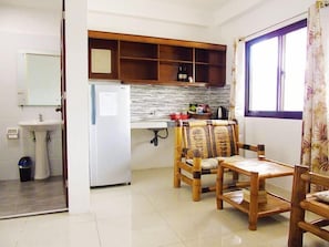 Cuina compacta amb nevera, un rentaplat i taula de dinar de fusta amb cadires.