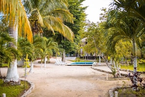 Un resort tropical con piscina, palmeras y una zona de arena.