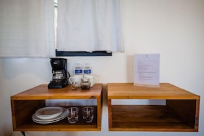 Una estación de café con cafetera, tazas y un menú sobre una mesa de madera.