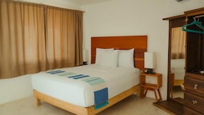Una habitación de hotel con cama, mesitas de noche, armario y espejo.