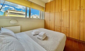 A bedroom with a bed, a window, and wooden wardrobes. - Hospitality Expert - Pefki Prestige Condo (Pefki)