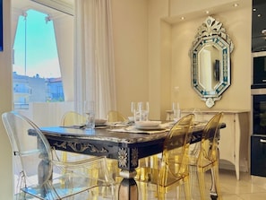 A dining area with a black table, clear chairs, and a decorative mirror on the wall. - Hospitality Expert - Pefki Prestige Condo (Pefki)