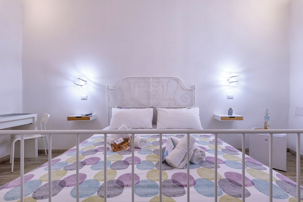 Een slaapkamer met een bed, nachtkastjes, een bureau en een stoel.