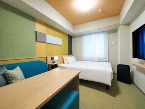 Une chambre d’hôtel équipée d’un lit, d’un bureau, d’une chaise, d’une télévision et d’une fenêtre avec des rideaux.