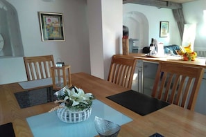 Ein Essbereich mit Holztisch, Stühlen, einer Blumenvase und einem gerahmten Bild an der Wand.