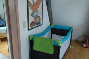 A child's playpen with a green towel, a wall-mounted picture of a vehicle, and a wooden floor. - Modernity meets history (Lübeck)