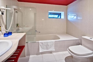 Un baño moderno con ducha envuelta en vidrio, bañera, inodoro y lavabo.