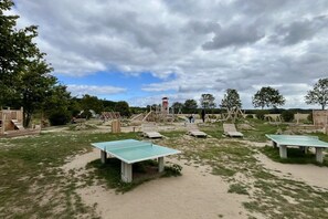 An outdoor recreational area with a ping pong table, swings, and a climbing structure. - Holiday apartment with 2 bedrooms (Bakenberg)