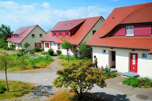 A row of houses with red roofs and white walls, a paved path, and greenery. - Holiday apartment with 2 bedrooms (Bakenberg)