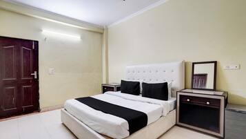 Una habitación de hotel con cama, mesita de noche, espejo y ventilador de techo.