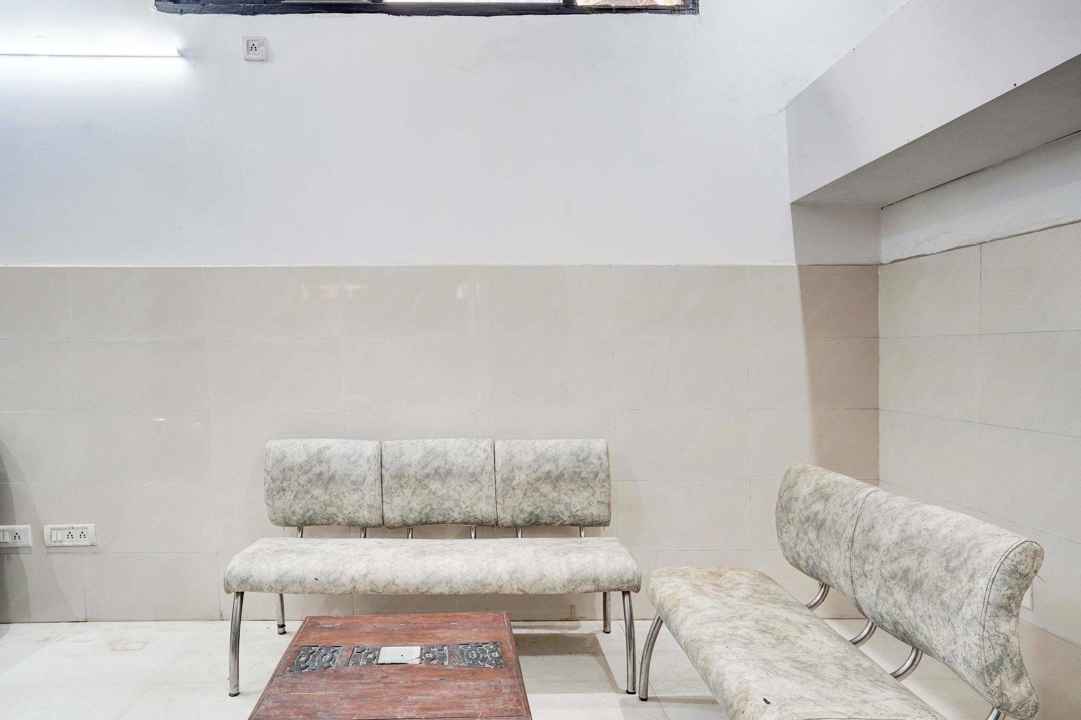 Un área de espera con una mesa de centro de madera, dos bancos acolchados y piso de baldosas.