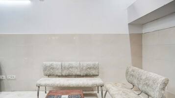 Un área de espera con una mesa de centro de madera, dos bancos acolchados y piso de baldosas.