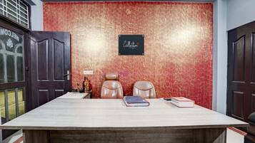 Una sala de conferencias con una mesa grande, dos sillones de cuero, un cartel en la pared y una puerta con ventana.