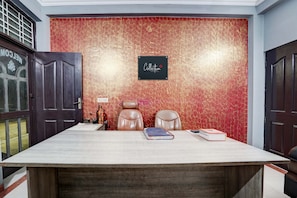 Una sala de conferencias con una mesa grande, dos sillones de cuero, un cartel en la pared y una puerta con ventana.