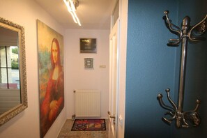 A hallway with a large painting, a coat rack, a radiator, and a door. - hollandferien.haus Strandperle 83 (Julianadorp aan zee)