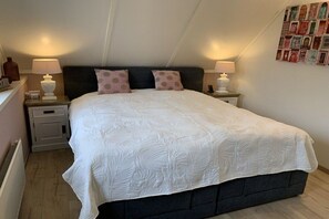 Quarto com uma cama grande, duas mesas de cabeceira e duas luminárias de parede.