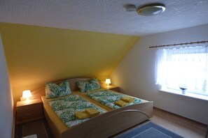 A bedroom with a bed, bedside tables, a window with curtains, and a ceiling light. - Holiday apartment with 1 bedroom (Fuhlendorf)