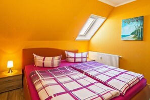 Ein Schlafzimmer mit Bett, Nachttisch, Lampe, Heizkörper und einem Bild an der Wand.