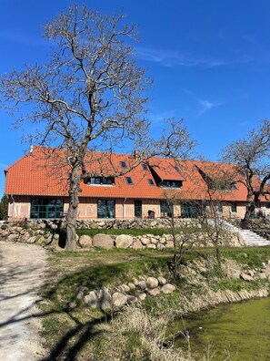 Ein Gebäude mit rotem Ziegeldach, Steinmauern und einer Steintreppe, die zum Eingang führt.
