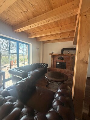 Ein gemütlicher Raum mit Ledersofa, rundem Tisch und Kamin aus Ziegelsteinen.