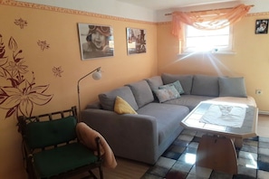 A living room with a sofa, a small table, a chair, and wall decorations. - Holiday apartment with 2 bedrooms (Sassnitz)