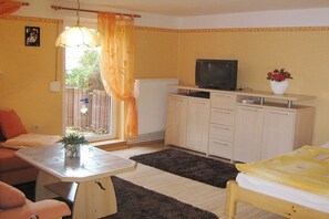 A compact room with a bed, a small table, a television, and a cabinet. - Holiday apartment with 2 bedrooms (Sassnitz)