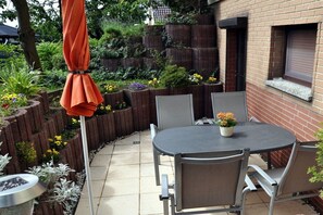 A patio with a round table and chairs, surrounded by raised planters with various flowers. - Holiday apartment with 2 bedrooms (Sassnitz)