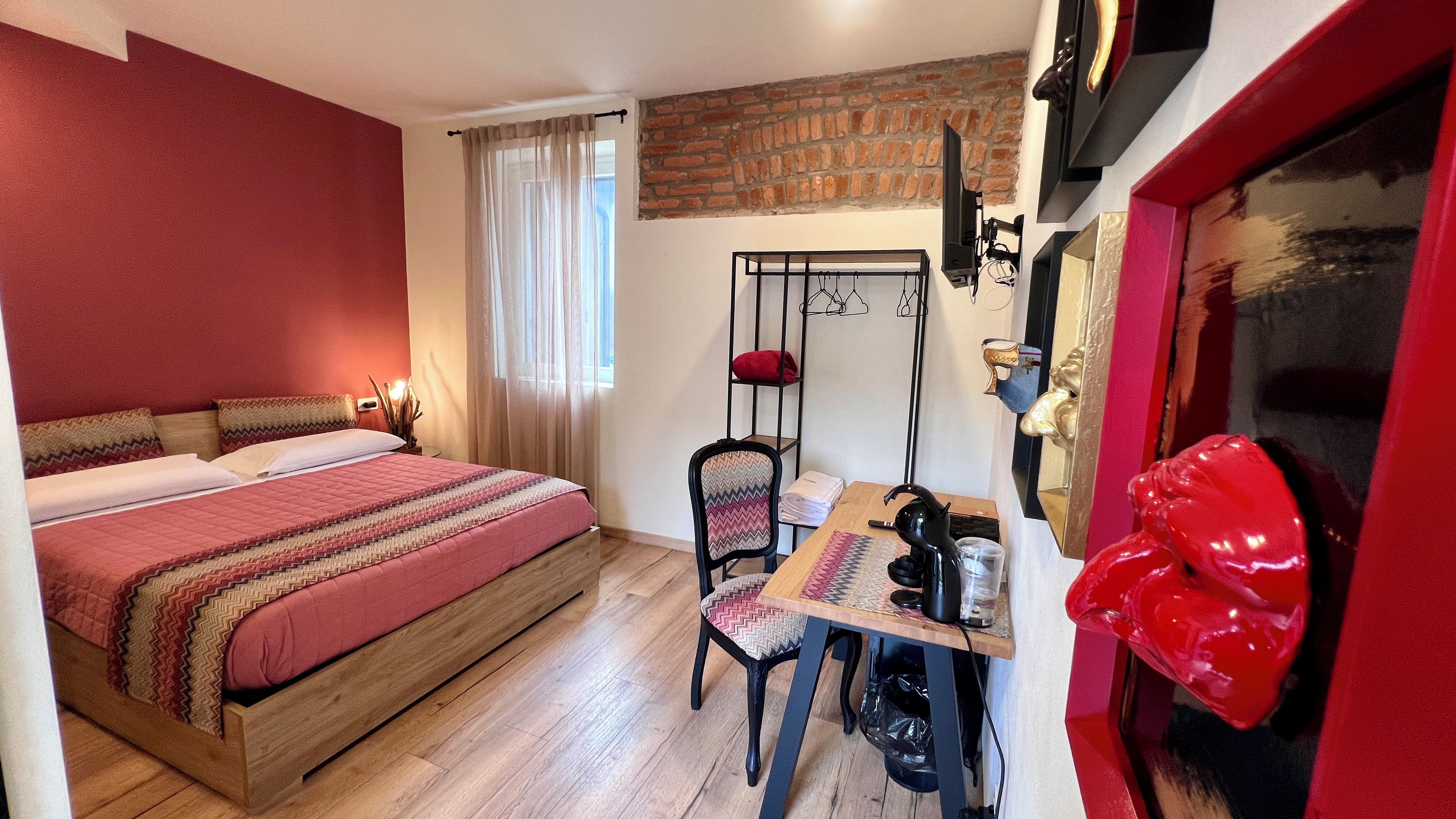 Une chambre à coucher avec un lit, un bureau, une chaise et une sculpture rouge.