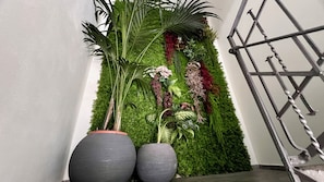A corner with a vertical garden wall, two large grey planters, and a metal spiral staircase.